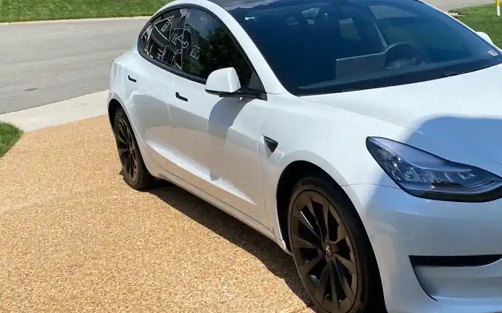 A White Telsa Model 3 in a driveway